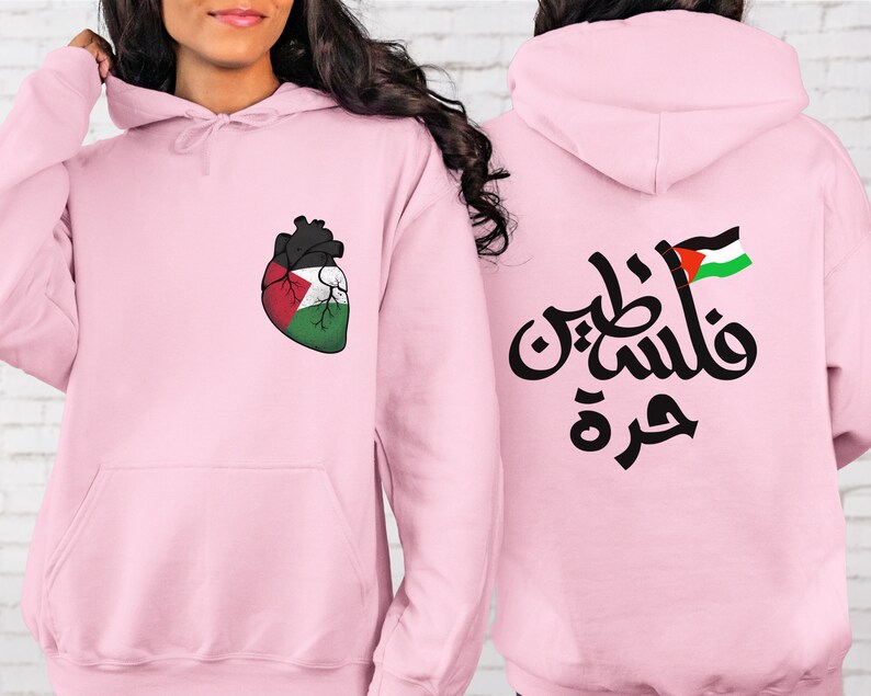 Może przedstawiać: R&oacute;żowa bluza z sercem w kształcie palestyńskiej flagi z przodu i arabskim napisem "Palestyna" z palestyńską flagą z tyłu.