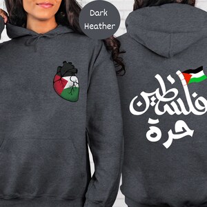 Może przedstawiać: Szara bluza z kapturem w kolorze ciemnego melanżu z sercem w barwach flagi palestyńskiej z przodu i arabskim tekstem "فلسطين حرة" (Palestyna jest wolna) z tyłu.