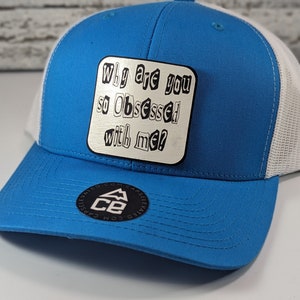 May include: A blue and white trucker hat with a white patch that says "Why are you so Obsessed with me?"
