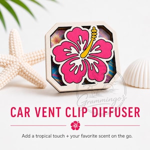 May include: A wooden car vent clip diffuser featuring a vibrant pink hibiscus flower design. The flower has yellow stamens and white outlines. The text "CAR VENT CLIP DIFFUSER" is displayed in pink. The diffuser adds a tropical touch.