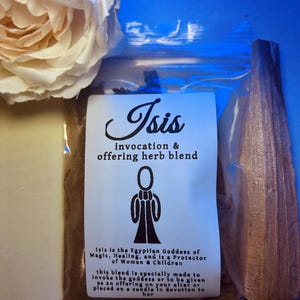 Puede incluir: Una pequeña bolsa de papel marrón con una etiqueta blanca que dice "Isis invocation & offering herb blend". La etiqueta también incluye una ilustración en blanco y negro de una persona con una túnica y una descripción de la diosa egipcia Isis.