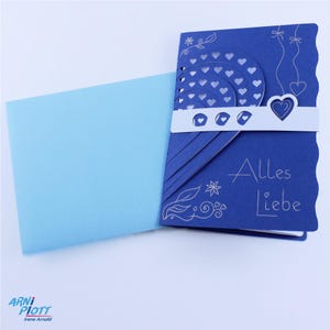 May include: A blue card with a white heart and the words "Alles Liebe" in white lettering. The card is folded in half and has a light blue envelope.