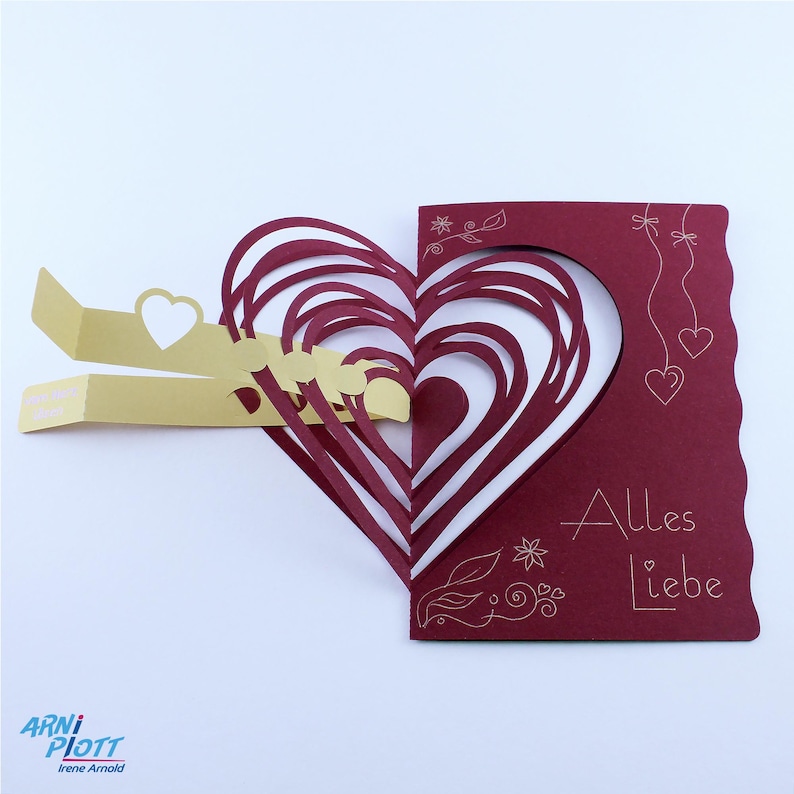May include: A red card with a pop-up heart design. The heart is made of multiple layers of red paper. The card has the text "Alles Liebe" written on it in white.