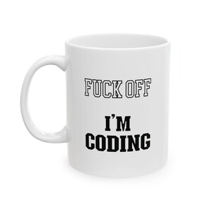 May include: White ceramic mug with the text "FUCK OFF I'M CODING" in black block letters. The mug has a curved handle and is suitable for hot or cold beverages. The mug is a humorous gift for programmers.