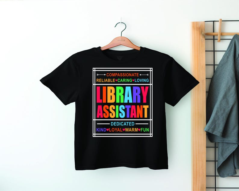 May include: Black t-shirt with a rainbow graphic that says "Library Assistant". The graphic is surrounded by a white box and includes the words "Compassionate", "Reliable", "Caring", "Loving", "Dedicated", "Kind", "Loyal", "Warm", and "Fun".