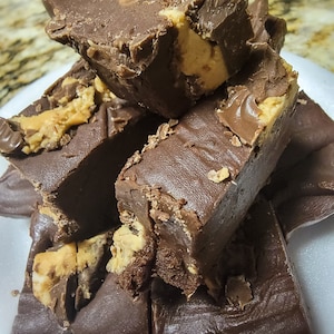 May include: A close-up of a stack of chocolate fudge squares with peanut butter swirls. The fudge is a rich brown color and the peanut butter swirls are a lighter brown.