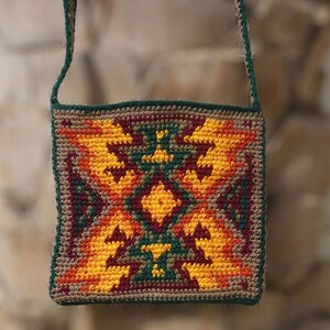 May include: A crocheted shoulder bag with a geometric pattern in shades of green, orange, yellow, and brown.