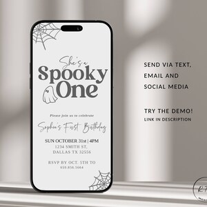 May include: A white and grey digital invitation for a first birthday party with a spooky theme. The invitation features a ghost, spiderwebs, and the text "She's a Spooky One". The invitation includes the date, time, and location of the party, as well as an RSVP contact.