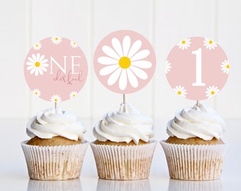 May include: Three pink and white cupcake toppers with daisy designs. One topper says "One Derful" with a large daisy in the center. Another topper has a large daisy in the center. The third topper has the number "1" in the center with smaller daisies around it.