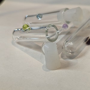 May include: A group of clear glass tubes with colorful glass beads inside. The tubes have white silicone caps on the ends.