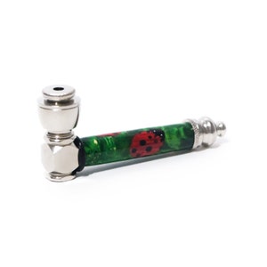 May include: A silver metal smoking pipe with a green and red ladybug design. The pipe has a bowl on one end and a mouthpiece on the other.