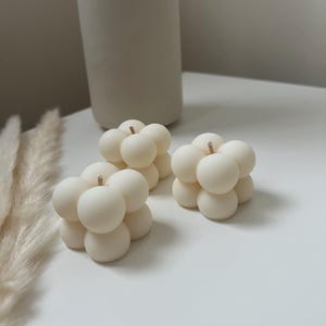 May include: Three small, white, round, bubble-shaped candles. Each candle has a small wick in the centre.