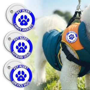 May include: Three white and blue pet alert badges with the text "I HAVE ANXIETY", "THYROID ISSUE", and "SERVICE DOG". A dog wears a blue and orange vest with a "PET ALERT" patch that says "VISUALLY IMPAIRED".
