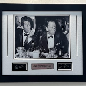 May include: A black and white framed photograph of Dean Martin and Frank Sinatra at a table with drinks. The display includes two signatures and a plaque with the text: I feel sorry for people who don't drink. When they wake up in the morning, that's as good as they're going to feel all day.