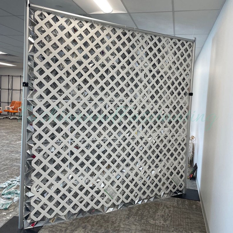 May include: A white plastic privacy screen with a diamond lattice pattern. The screen is made of a lightweight material and is easy to assemble. It is perfect for creating a temporary divider in a room or office.