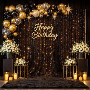 May include: A festive birthday party backdrop with gold and black balloons, a black curtain with string lights, and a gold "Happy Birthday" sign. White floral arrangements and candles add to the celebratory atmosphere.