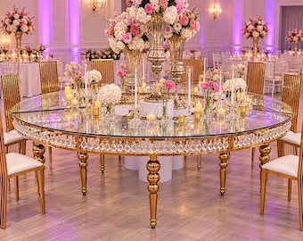 May include: A large round glass dining table with a gold metal frame and hanging crystal accents. The table is decorated with tall gold vases filled with pink and white floral arrangements, numerous glass candle holders, and white candles.