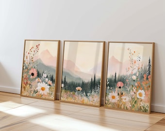 May include: Three framed prints of a watercolor painting depicting a field of wildflowers in front of a mountain range. The prints are in a light wood frame and have a soft, pastel color palette.