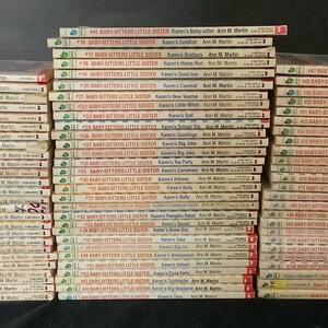 Puede incluir: Una colecci&oacute;n de 48 libros de bolsillo, todos titulados "Baby-Sitters Little Sister" con diferentes colores de lomo. Los libros est&aacute;n apilados en tres columnas, cada columna contiene 16 libros. Los libros son todos del mismo estilo, con un fondo blanco y texto rojo y verde. Los t&iacute;tulos de los libros son visibles, y todos presentan el nombre "Karen's" seguido de una actividad o evento diferente. La autora, Ann M. Martin, tambi&eacute;n es visible en cada libro.