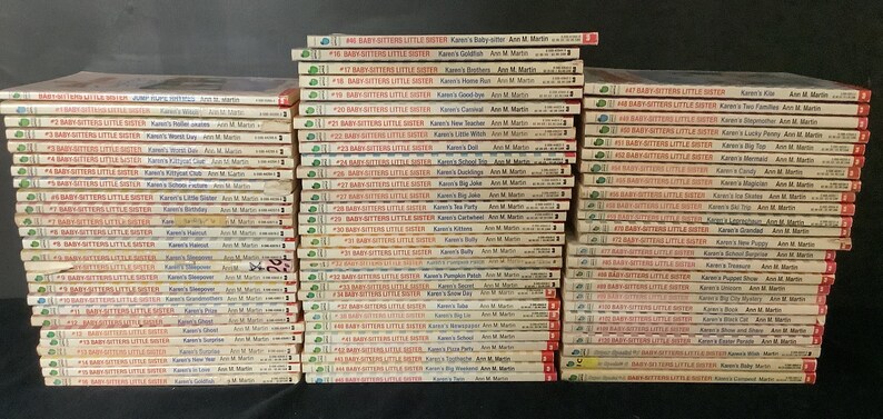 Puede incluir: Una colecci&oacute;n de 48 libros de bolsillo, todos titulados "Baby-Sitters Little Sister" con diferentes colores de lomo. Los libros est&aacute;n apilados en tres columnas, cada columna contiene 16 libros. Los libros son todos del mismo estilo, con un fondo blanco y texto rojo y verde. Los t&iacute;tulos de los libros son visibles, y todos presentan el nombre "Karen's" seguido de una actividad o evento diferente. La autora, Ann M. Martin, tambi&eacute;n es visible en cada libro.