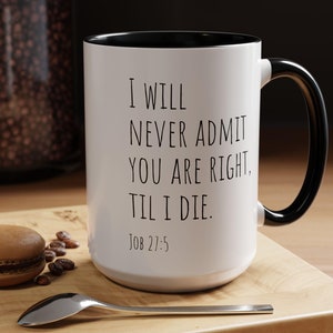 Peut inclure: Une tasse à café blanche avec une anse et un bord noirs. La tasse porte une inscription noire qui dit "I WILL NEVER ADMIT YOU ARE RIGHT, TIL I DIE. JOB 27:5"