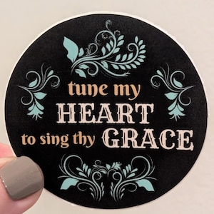 May include: Black and white round sticker with a teal floral design. The text "tune my HEART to sing thy GRACE" is written in a decorative font.