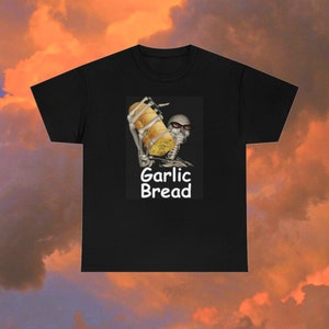 Könnte beinhalten: Schwarzes T-Shirt mit einer Grafik eines Skeletts mit Sonnenbrille, das ein Knoblauchbrot hält. Die Worte "Garlic Bread" sind darunter in Weiß gedruckt. Das T-Shirt ist aus einem weichen Material.