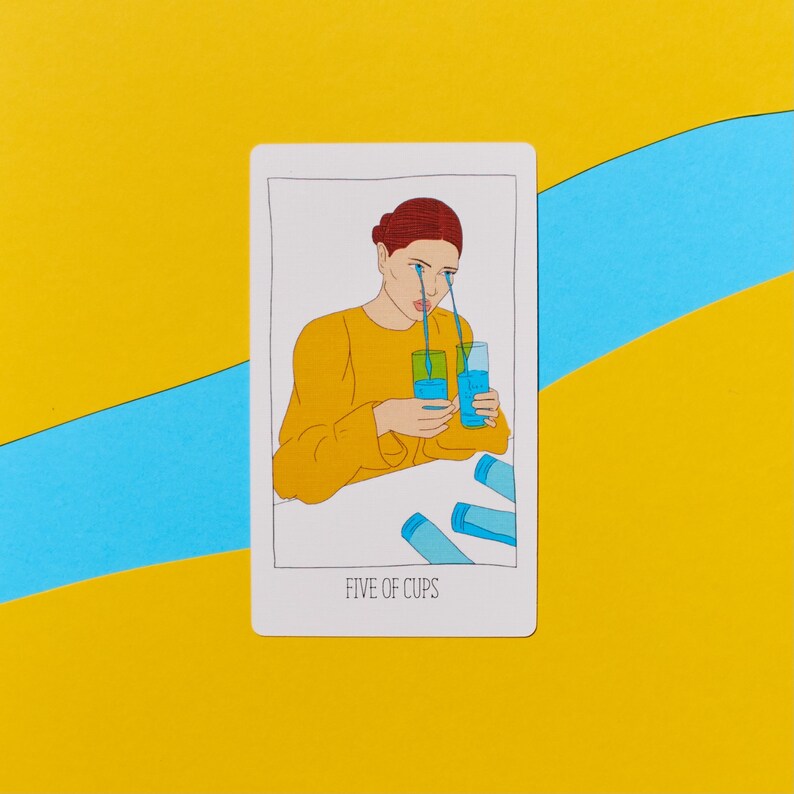 K&ouml;nnte beinhalten: Eine Tarotkarten-Illustration, die eine Person mit blauen Tr&auml;nen zeigt, die ihr Gesicht herunterlaufen, und zwei Tassen mit Fl&uuml;ssigkeit h&auml;lt. Die Karte tr&auml;gt den Titel "F&uuml;nf der Kelche".