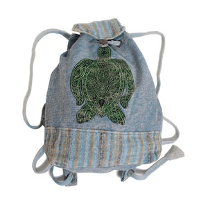 May include: A blue denim drawstring backpack with a green embroidered turtle design. The backpack has a striped fabric trim.