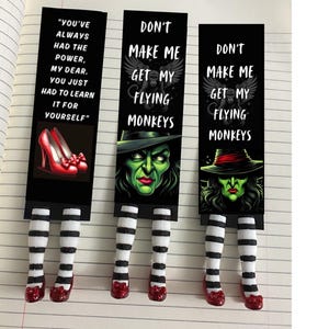 May include: Three black and white striped bookmark designs with red ruby slippers. The top of each bookmark features a witch with green skin and a black hat. The text on the bookmarks reads "Don't make me get my flying monkeys".