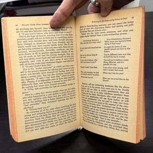 May include: Open book with text on pages 62 and 63. The text discusses victimizing sentences and how to avoid them. The pages are yellowed with age, suggesting an older publication. The book is open, with a hand visible.