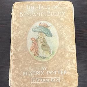 May include: The Tale of Benjamin Bunny by Beatrix Potter, a vintage children's book with a cover illustration of a rabbit wearing a blue hat and holding a red scarf.