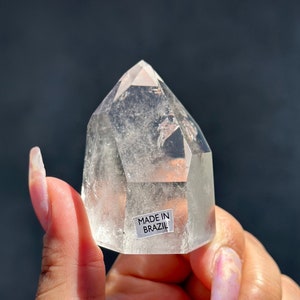 May include: A clear quartz crystal point with a label that reads "Made in Brazil".