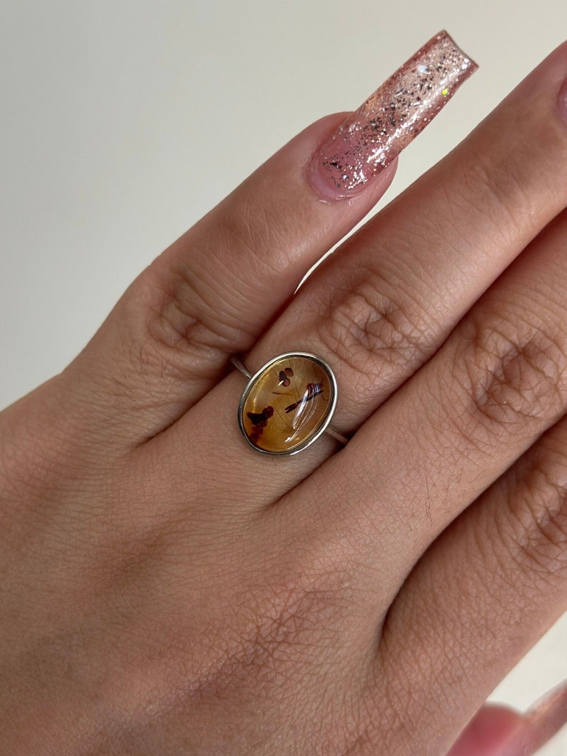 Op de afbeelding: Een zilveren ring met een bruine, ovale steen in het midden. De steen heeft een uniek patroon van bruine en zwarte insluitsels.