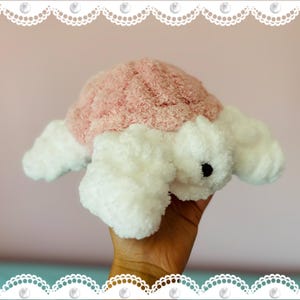 May include: A plush turtle toy with a pink shell and white body. The turtle has a soft, textured appearance and a small black eye. The toy is designed to be cuddly and is likely intended for children.