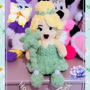 May include: Hand-knitted Tinkerbell doll with a green dress and star wand. The doll has yellow hair and is surrounded by other knitted character dolls. The text "Hand Knit Tink" is visible.