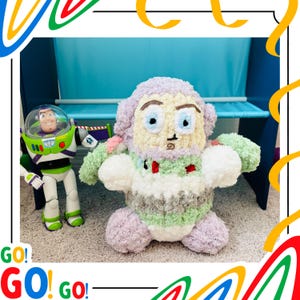 May include: A handmade, plush Buzz Lightyear doll with a light purple head, green arms, and a white and green body. A Buzz Lightyear action figure stands to the left. The word "GO!" is written in red and green.