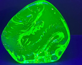 May include: A bright green glass paperweight with a swirling, abstract design. The glass is translucent and has a slightly cloudy appearance.