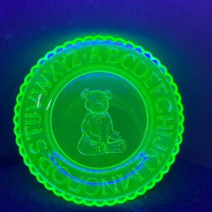 May include: A green glass plate with a scalloped edge. The plate has a teddy bear design in the center and the alphabet around the edge. The letters are "A B C D E F G H I J K L M N O P Q R S T U V W X Y Z".