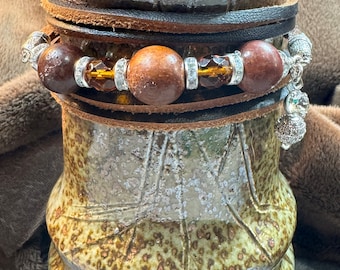 Wrap bracelet in brown leather, wooden beads, and crystals run across the center front.  Lobster claw closure.