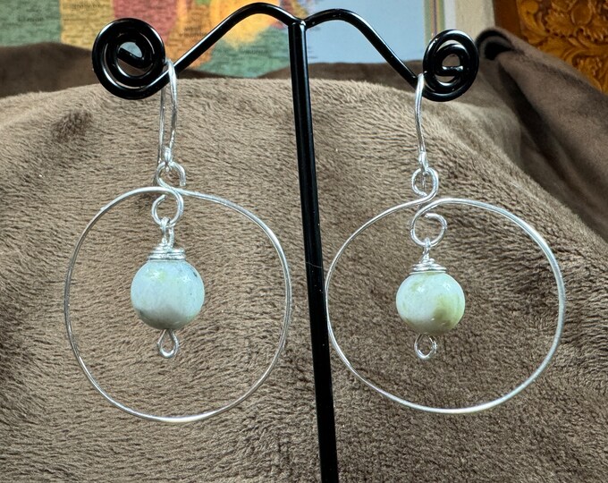 Handmade 1 1/2” round silver wrapped hoop with a white quartz crystal stone bead drop in the center. Attached with French hook ear wires.