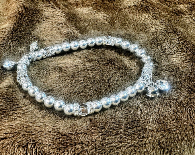 Handmade Bracelet of Artisan jewelry made of silver beads, crystals, and rhinestone spacers with 4 rhinestone charms. 7 1/4” Elastic bling!