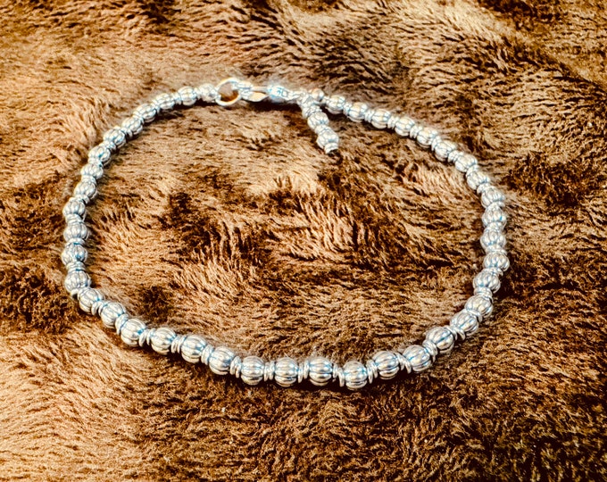 Small silver oval-shaped silver beaded bracelet on regular wire. Silver beaded charm. Lobster claw clasp. 7 3/4” Part of 3 bracelets.