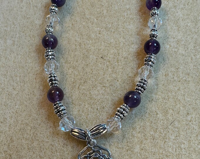 An elastic stretch bracelet made of amethyst and crystal beads in a beaded pattern.