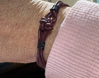 Bracciale celtico in pelle marrone, stile boho con nodo celtico e rivestimento in seta su pelle nera. Chiusura a moschettone con ciondolo in strass. Regalo per lei.