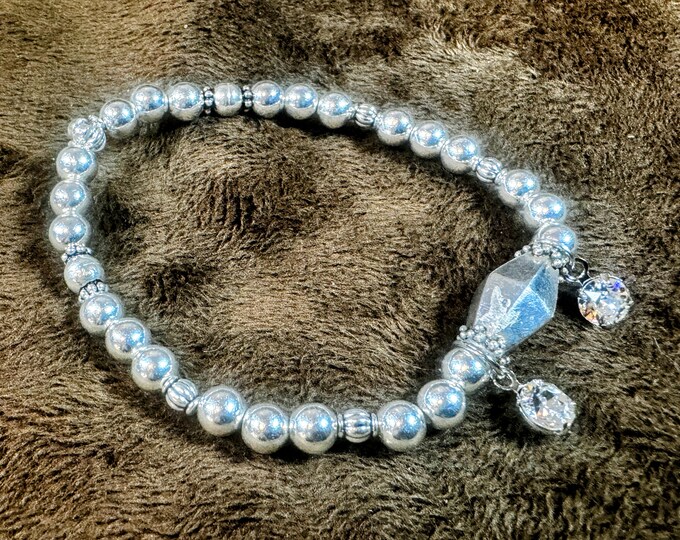 Large centered silver bead stretch elastic bracelet with smaller 6mm silver beads and a rhinestone charm. 7 1/4”. Handmade.