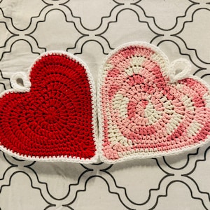 May include: Two crocheted heart-shaped pot holders, one red and one pink and white.