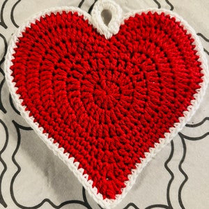 May include: A red crocheted heart-shaped pot holder with a white crocheted border and a loop at the top.