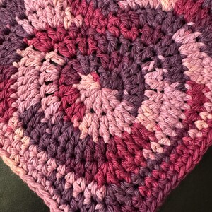 May include: A heart-shaped crocheted dishcloth in shades of pink, purple, and burgundy.