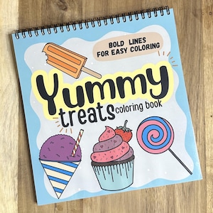 May include: A blue coloring book with the title "Yummy treats coloring book" and the words "Bold lines for easy coloring" in a white box. The cover features illustrations of a popsicle, a snow cone, a cupcake, and a lollipop.